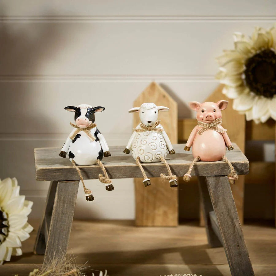 Pig, cow and sheep farm animal shelf sitter ornaments in neutral country style, sitting on a wooden windowsill with dangling legs