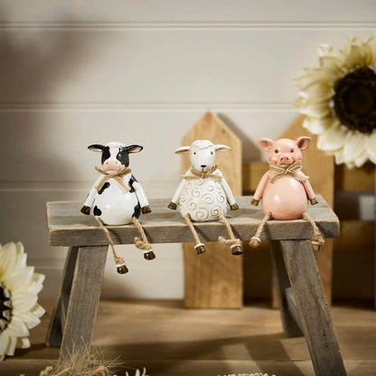Pig, cow and sheep farm animal shelf sitter ornaments in neutral country style, sitting on a wooden windowsill with dangling legs