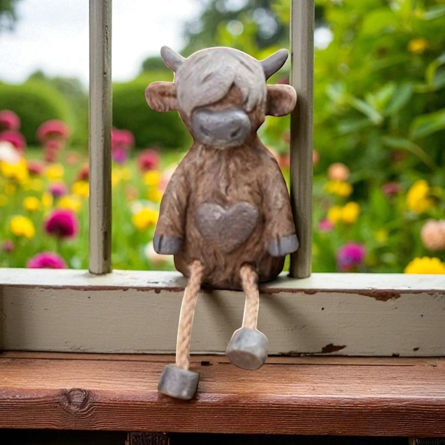 Highland cow shelf sitter ornament with dangling legs on wooden shelf
