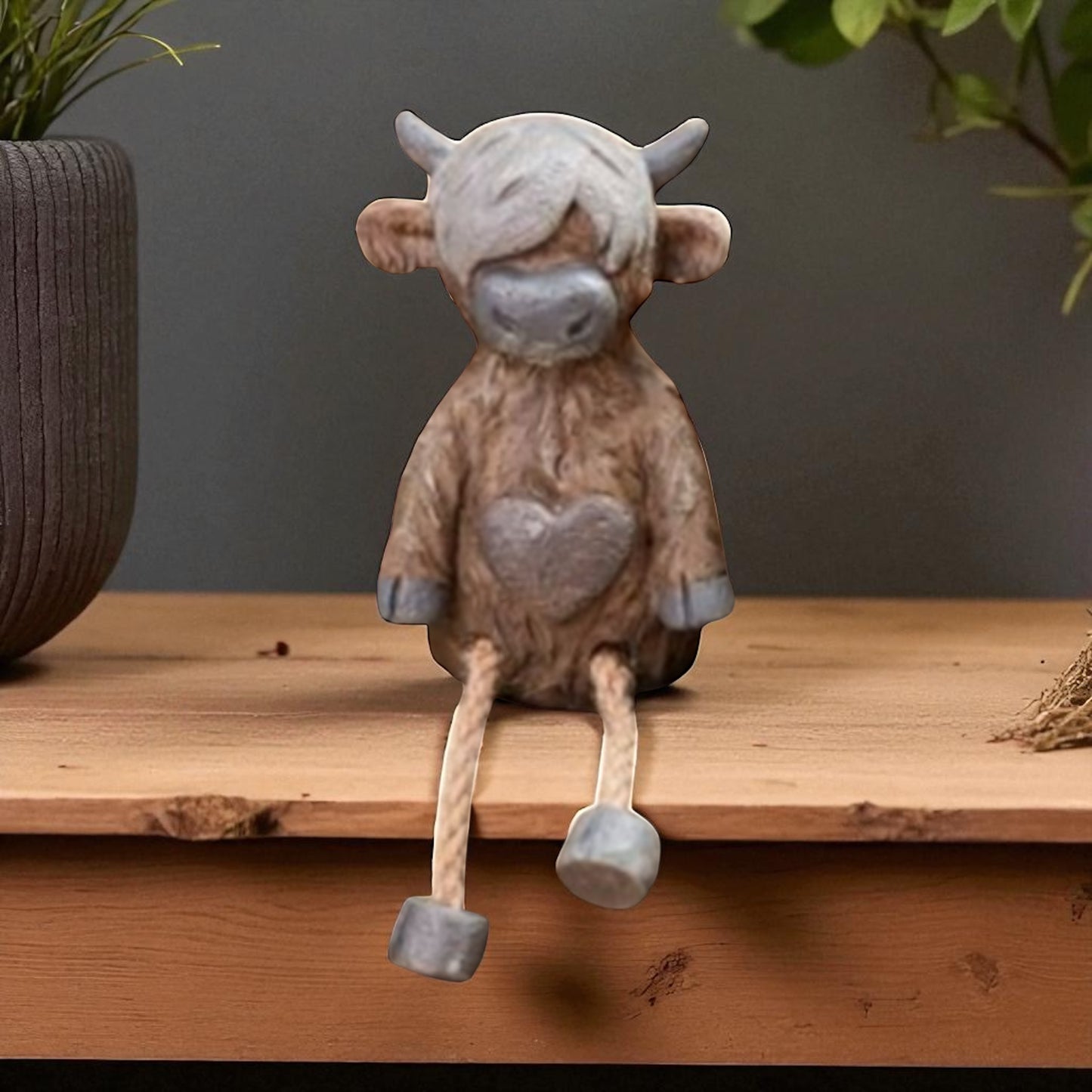 Highland cow shelf sitter ornament with dangling legs on wooden shelf
