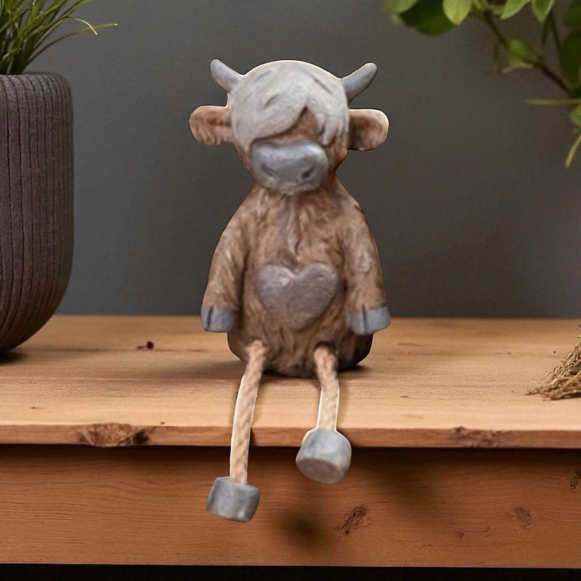 Highland cow shelf sitter ornament with dangling legs on wooden shelf
