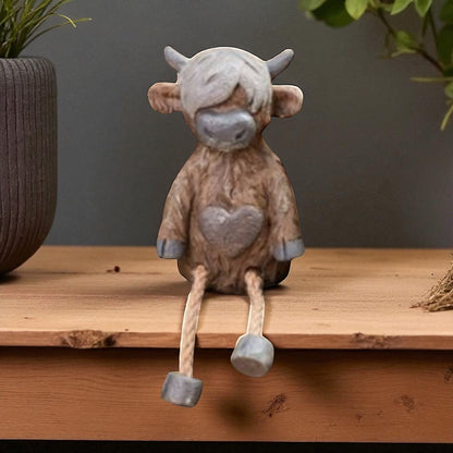 Highland cow shelf sitter ornament with dangling legs on wooden shelf
